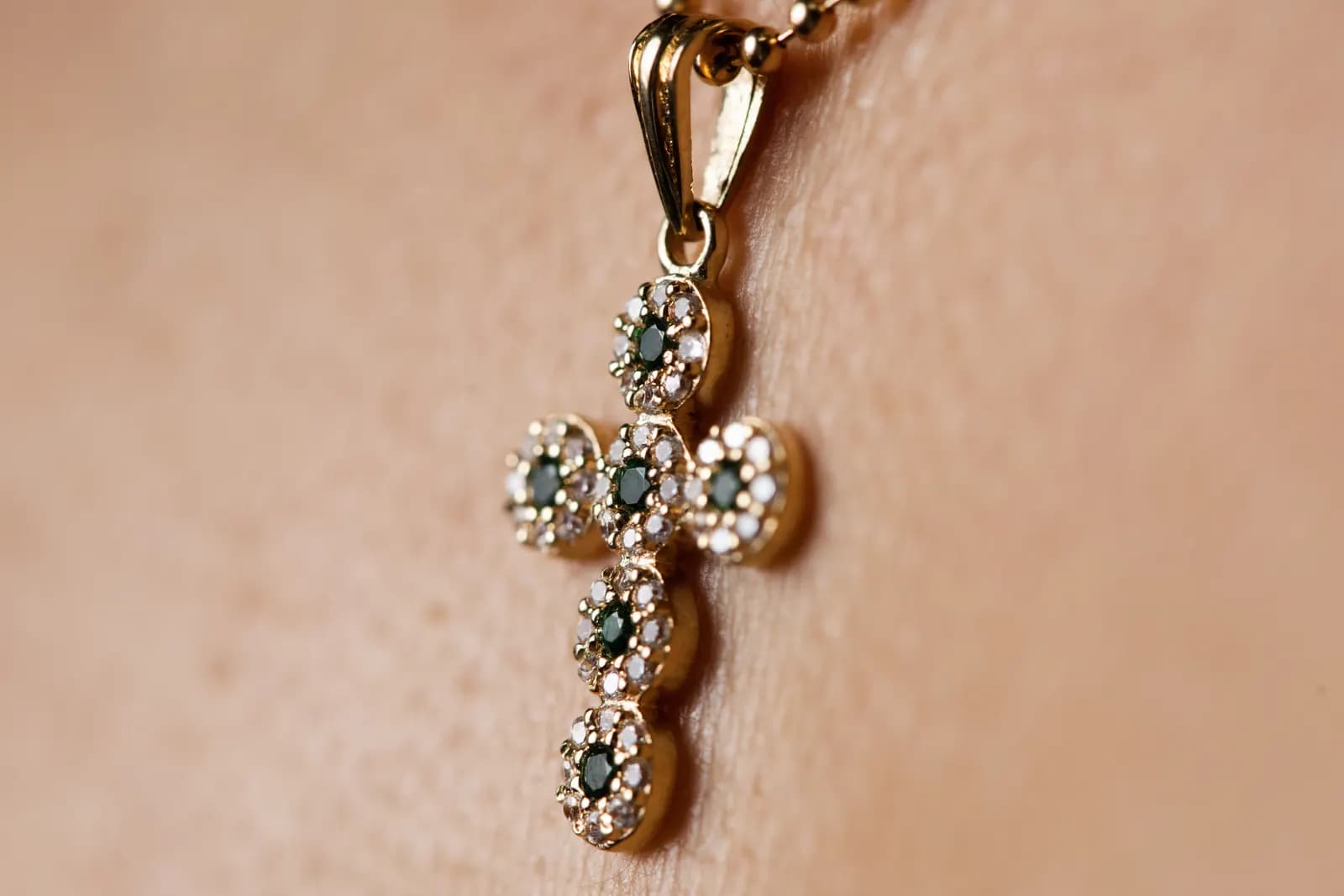 Dije de cruz en oro con piedras oscuras